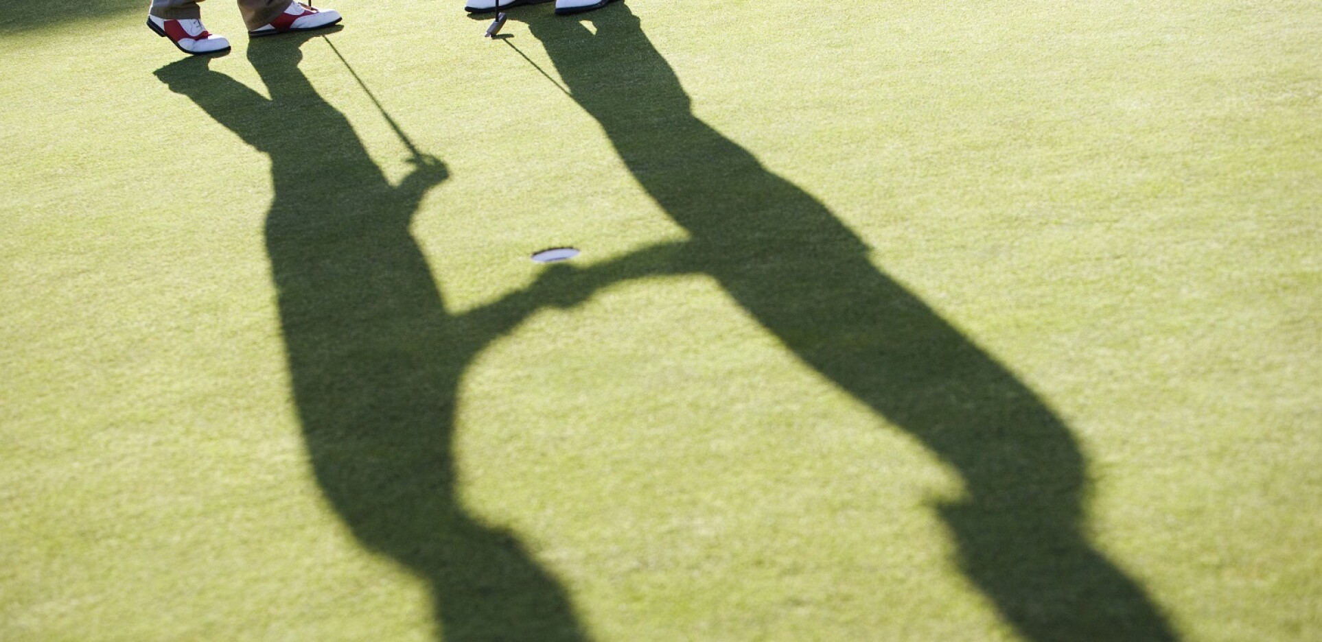 Shadow of golfers shaking hands on golf course